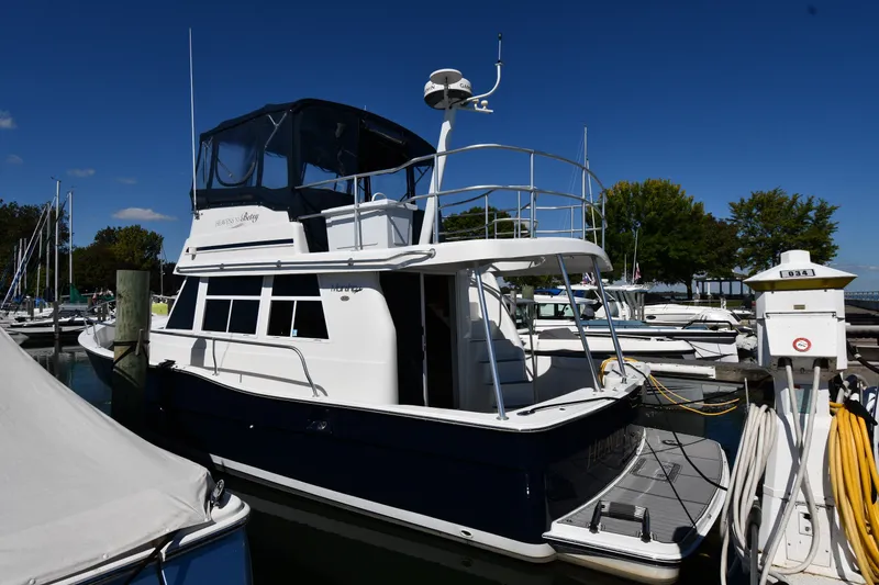 The Image of 2000 Mainship 390 Trawler docked at marina under clear blue sky. - 0