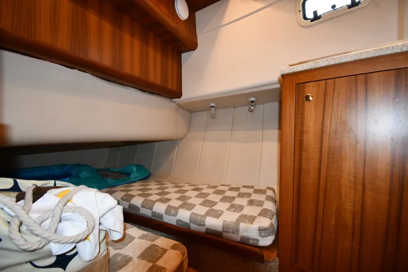Slide: The Image of Cozy cabin interior of 2000 Mainship 390 Trawler with wooden cabinetry and checkered bedding. - 35