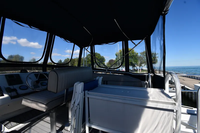 Slide: The Image of Interior view of 2000 Mainship 390 Trawler with seating and steering wheel, docked by the water. - 21