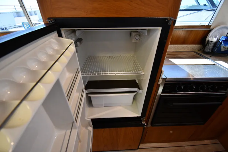 Slide: The Image of Open refrigerator in 2000 Mainship 390 Trawler kitchen, showcasing interior storage space. - 44