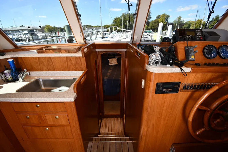 Slide: The Image of Interior of 2000 Mainship 390 Trawler with helm, sink, and wooden cabinetry. - 24