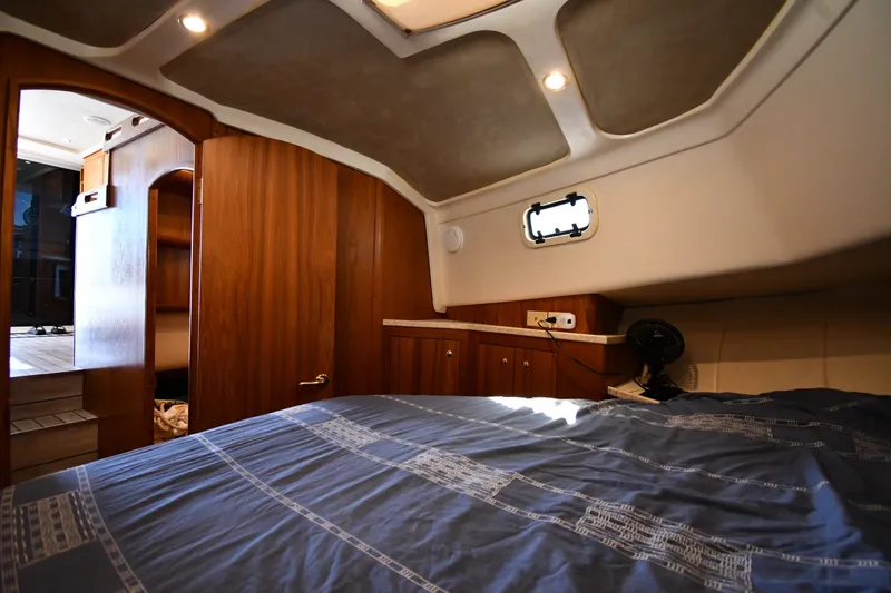 Slide: The Image of Cozy cabin interior of 2000 Mainship 390 Trawler with wood paneling and bed. - 29