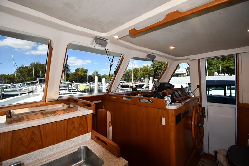 Slide: The Image of Interior view of a 2000 Mainship 390 Trawler helm with wooden accents and marina backdrop. - 46