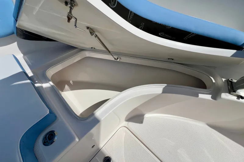 Slide: The Image of 2024 Robalo R222 Center Console boat storage compartment with open hatch and blue seating. - 18