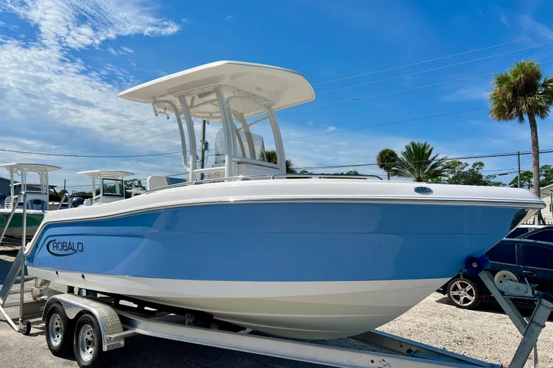 The Image of 2024 Robalo R222 Center Console boat on trailer under clear blue sky. - 1
