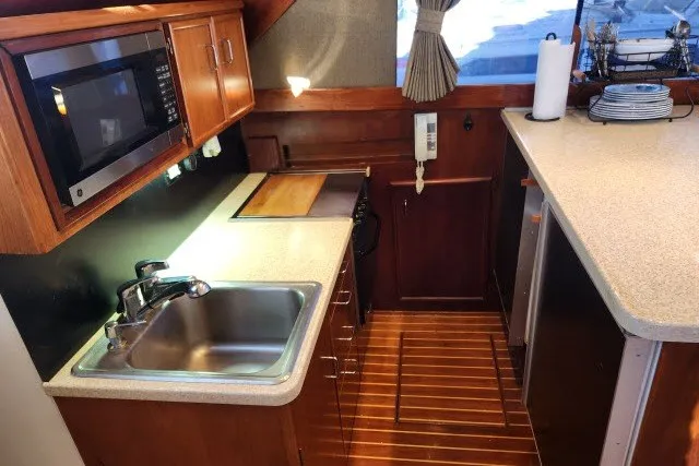 Slide: The Image of 1987 Ocean Yachts 48 Super Sport galley with sink, microwave, and wooden cabinetry. - 16