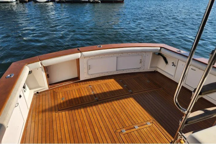 Slide: The Image of 1987 Ocean Yachts 48 Super Sport boat deck with teak flooring, docked on calm water. - 40