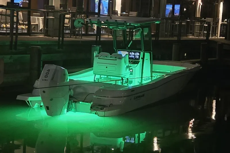 Slide: The Image of 2024 Caymas 281 HB boat illuminated with green lights at night, docked by a waterfront. - 1