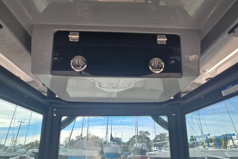 Slide: The Image of 2024 Caymas 281 HB boat interior storage compartment with secure latches, marina view. - 19