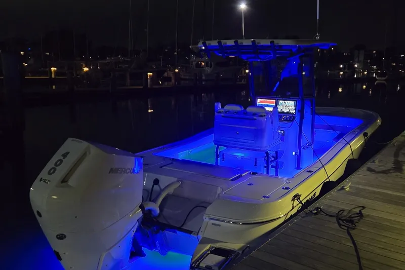 Slide: The Image of 2024 Caymas 281 HB boat illuminated with blue lights at night, docked in a marina. - 44