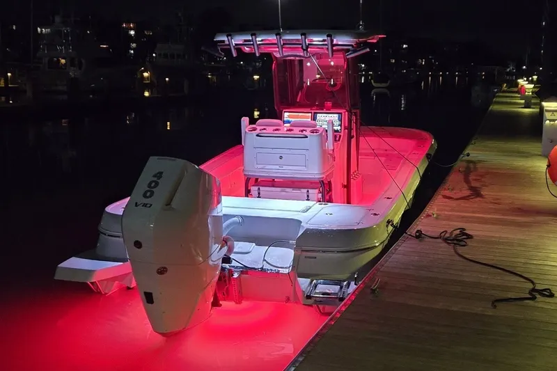 Slide: The Image of 2024 Caymas 281 HB boat illuminated with red lights at night, docked by the pier. - 43