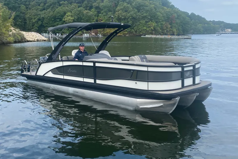 Slide: The Image of 2023 Barletta Lusso 25UCA pontoon boat on a serene lake with lush green surroundings. - 3