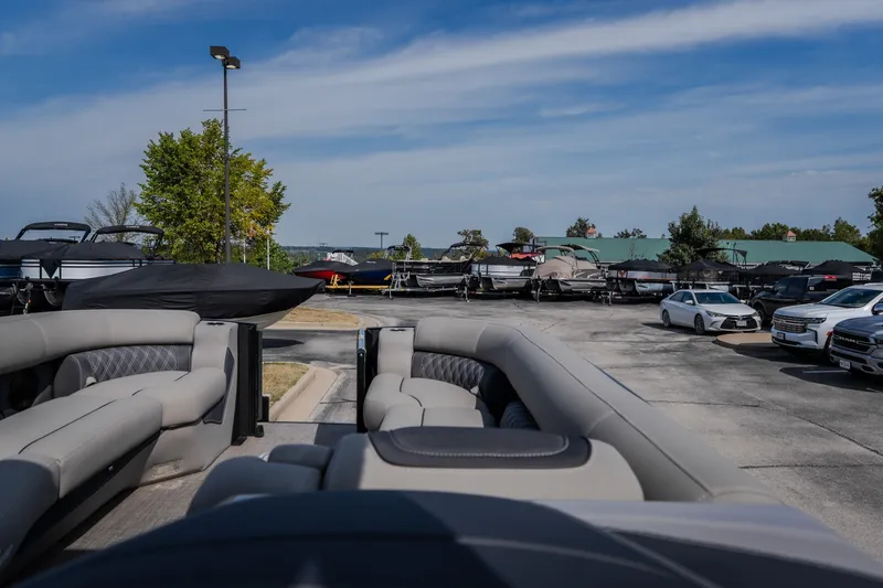Slide: The Image of 2023 Barletta Lusso 25UCA pontoon boat in a dealership lot with cars and trees. - 28