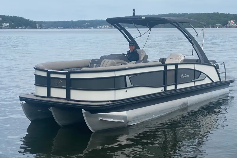 Slide: The Image of 2023 Barletta Lusso 25UCA pontoon boat on a calm lake with a person onboard. - 2