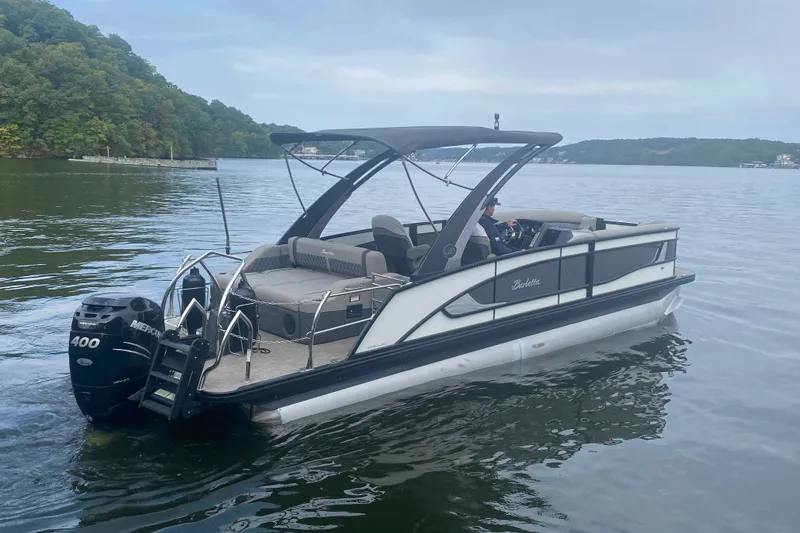 Slide: The Image of 2023 Barletta Lusso 25UCA pontoon boat cruising on a serene lake. - 4