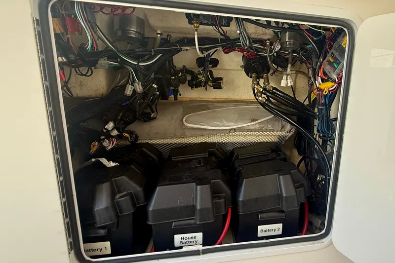Slide: The Image of 2014 Regulator 28 Forward Seating boat battery compartment with wiring and labeled batteries. - 18