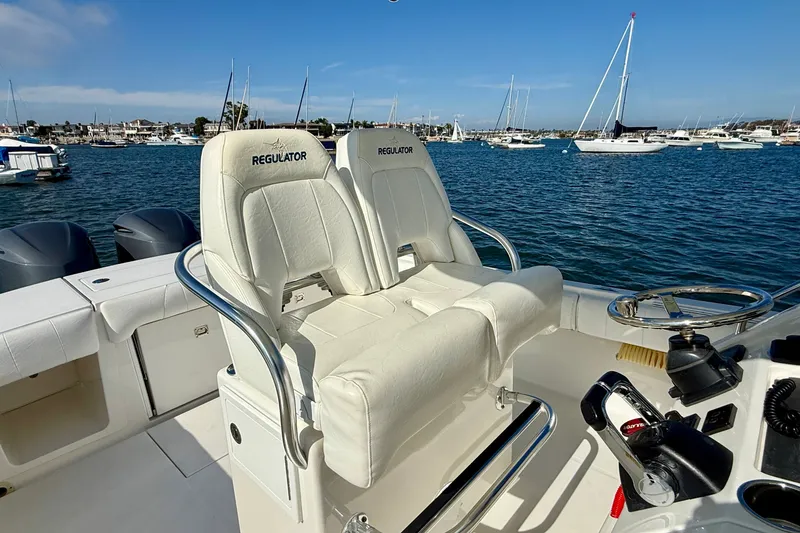 Slide: The Image of 2014 Regulator 28 Forward Seating boat with dual seats, steering wheel, and ocean view. - 13