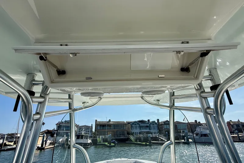 Slide: The Image of 2014 Regulator 28 Forward Seating boat with open storage compartment, docked near waterfront homes. - 14