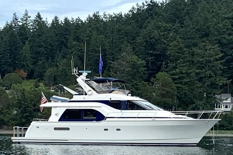 Slide: The Image of 1996 Queenship yacht on calm water, surrounded by lush green forest. - 0