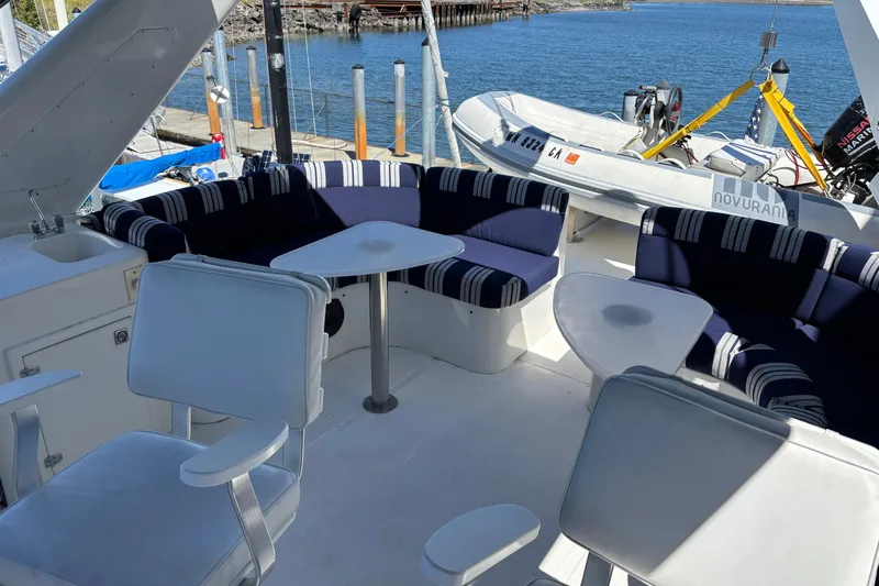Slide: The Image of Luxurious 1996 Queenship yacht deck with seating and a small boat in the background. - 15