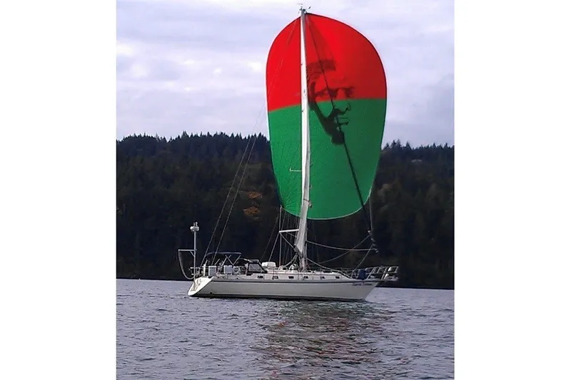 The Image of Een Caliber 40 zeilboot uit 2002 met een rood-groene spinnaker zeilt op kalm water. - 0