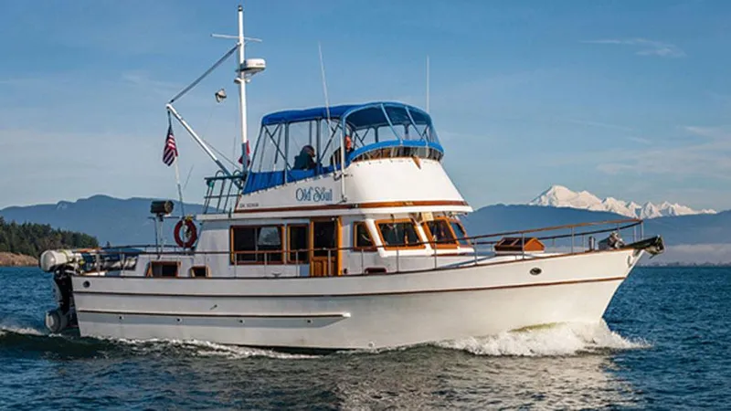The Image of 1980 CHB Trawler cruising on open water with mountains in the background. - 1