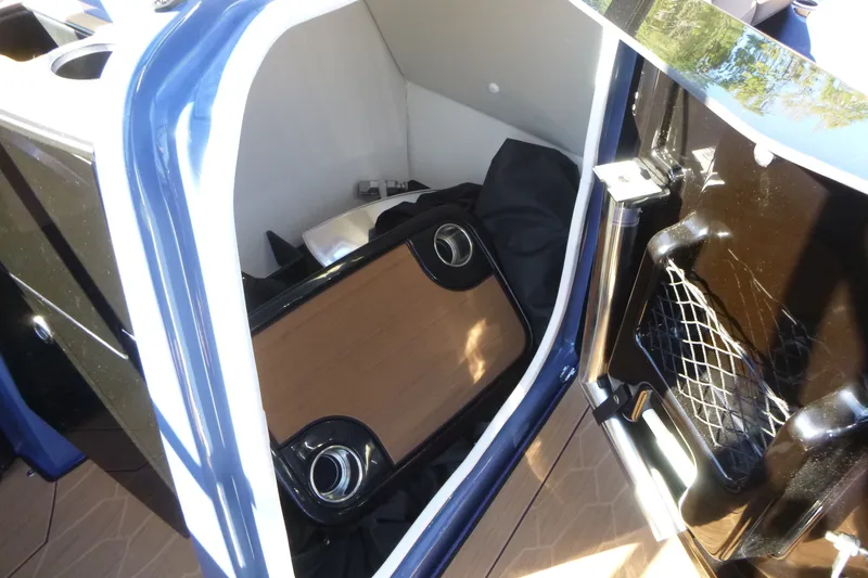 Slide: The Image of Interior storage compartment of 2024 Yamaha Boats 255XD, featuring a wooden table and netted pocket. - 16