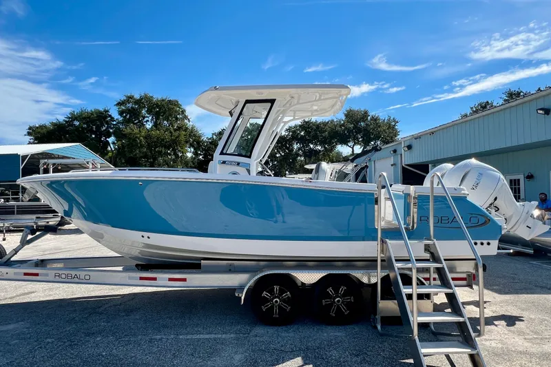 The Image of 2027 Robalo R250 Center Console boat on trailer, blue hull, outdoor setting. - 1