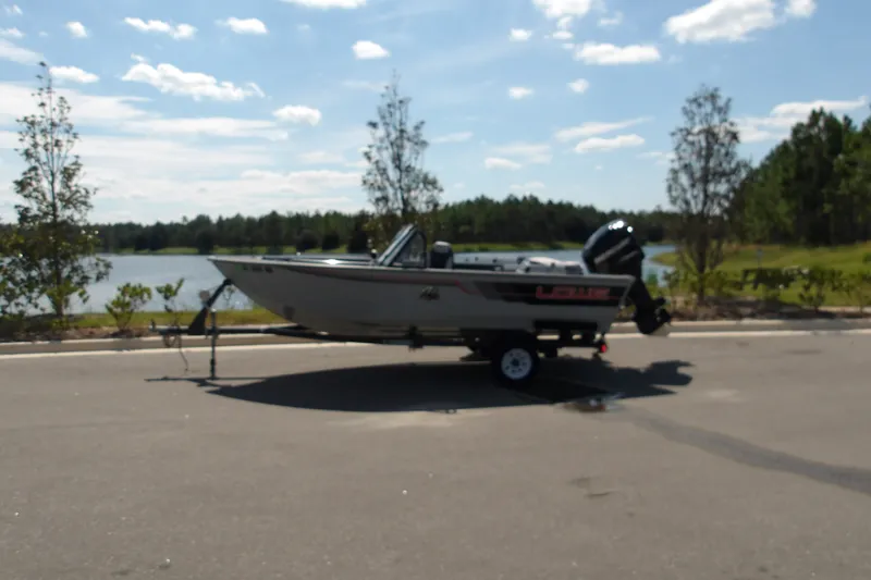 The Image of 1991 Lowe Fish & Ski 1730 boat on trailer by a scenic lake. - 0