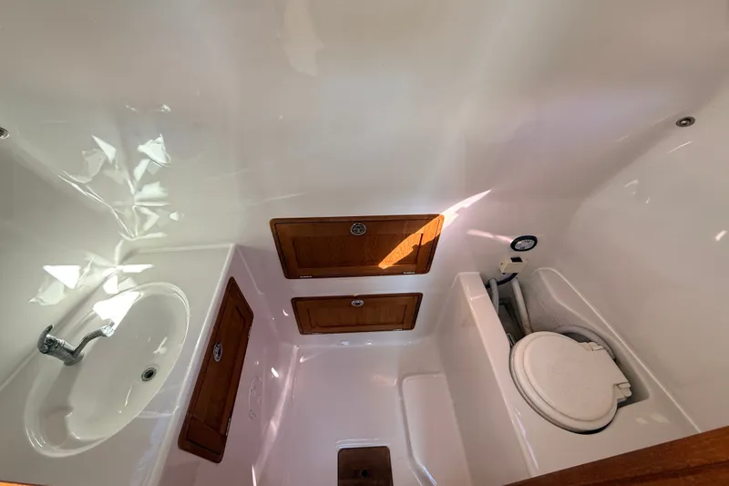 Slide: The Image of 2011 Protector Tauranga 38 boat bathroom with sink, toilet, and wooden storage cabinets. - 44