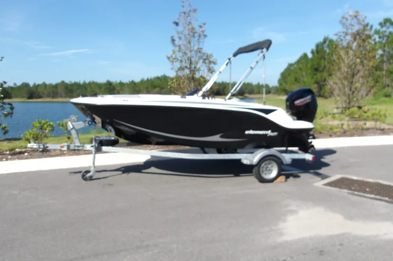 The Image of 2023 Bayliner Element M15 boat on trailer by a lake, sunny day. - 0