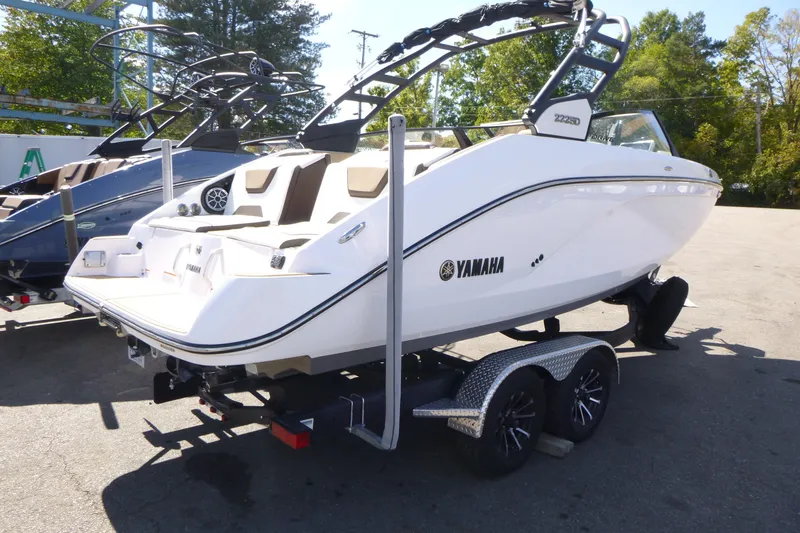 Slide: The Image of 2023 Yamaha Boats 222SD on trailer, sleek white design, parked outdoors. - 2