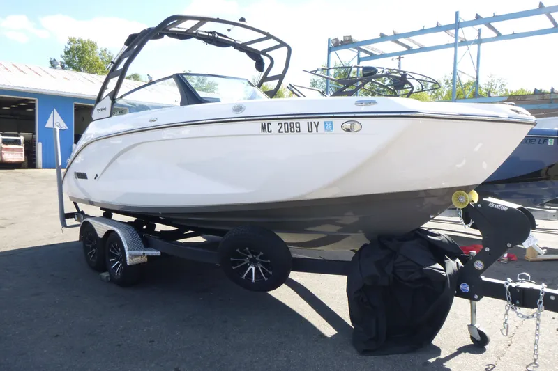Slide: The Image of 2023 Yamaha Boats 222SD on trailer, parked outdoors near a blue building. - 3