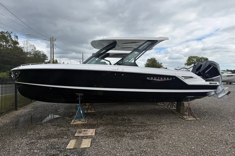 The Image of 2027 Monterey Elite 30 OB boat displayed on stands, featuring sleek black and white design. - 0