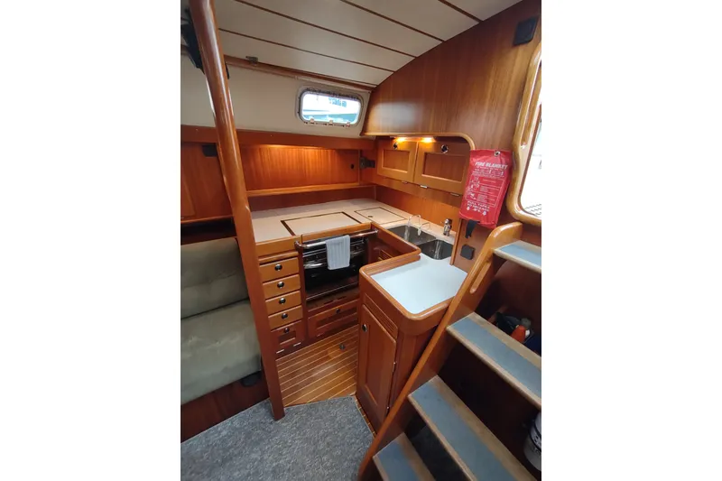 Slide: The Image of Interior of 2005 Hallberg-Rassy 43 sailboat, featuring a compact wooden kitchen area. - 37