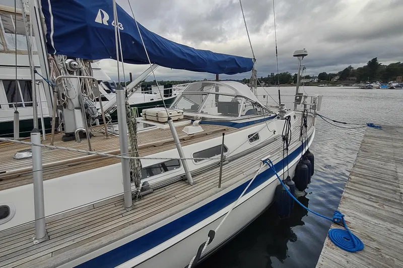 Slide: The Image of 2005 Hallberg-Rassy 43 sailboat docked, featuring a sleek design and blue accents. - 14