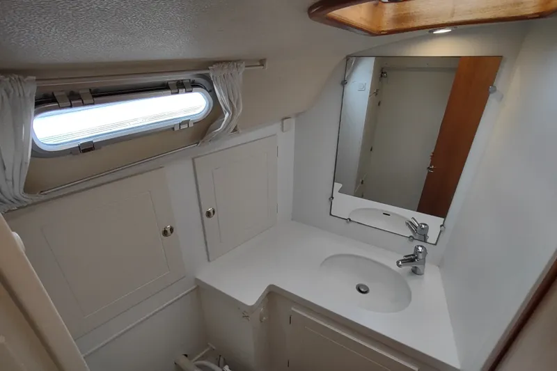 Slide: The Image of Hallberg-Rassy 43 (2005) yacht bathroom with sink, mirror, and porthole window. - 48