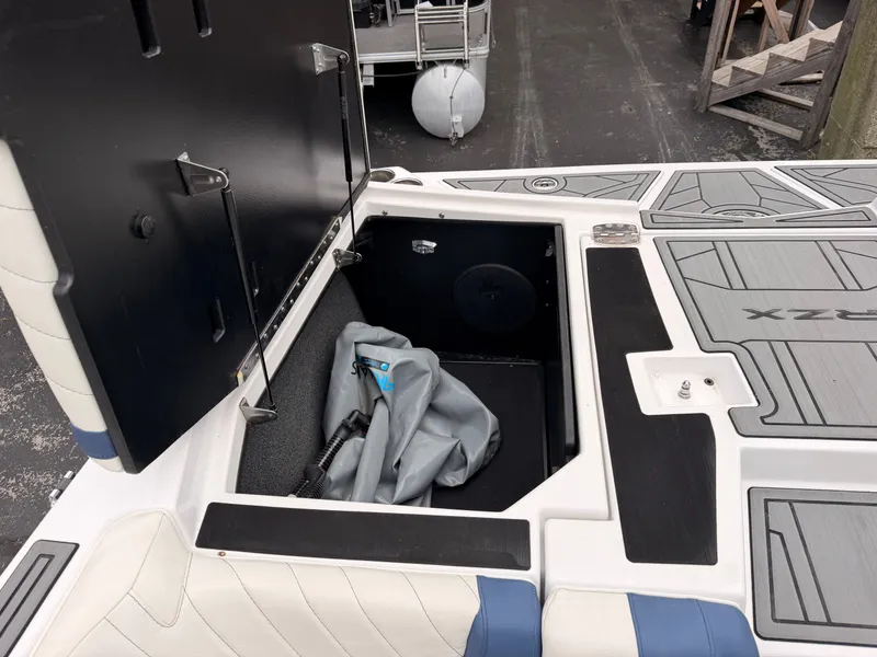 Slide: The Image of An open storage compartment on a boat with gray and blue upholstery and a black lid. - 14