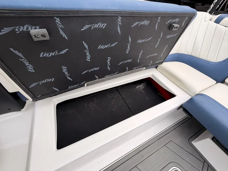 Slide: The Image of An open storage compartment in a boat with Tigé logo on the cover. - 20