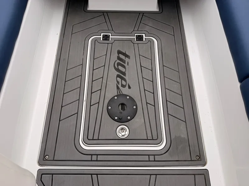 Slide: The Image of The image shows the floor of a 2021 Tigé 22RZX boat with gray decking and the Tigé logo. - 27