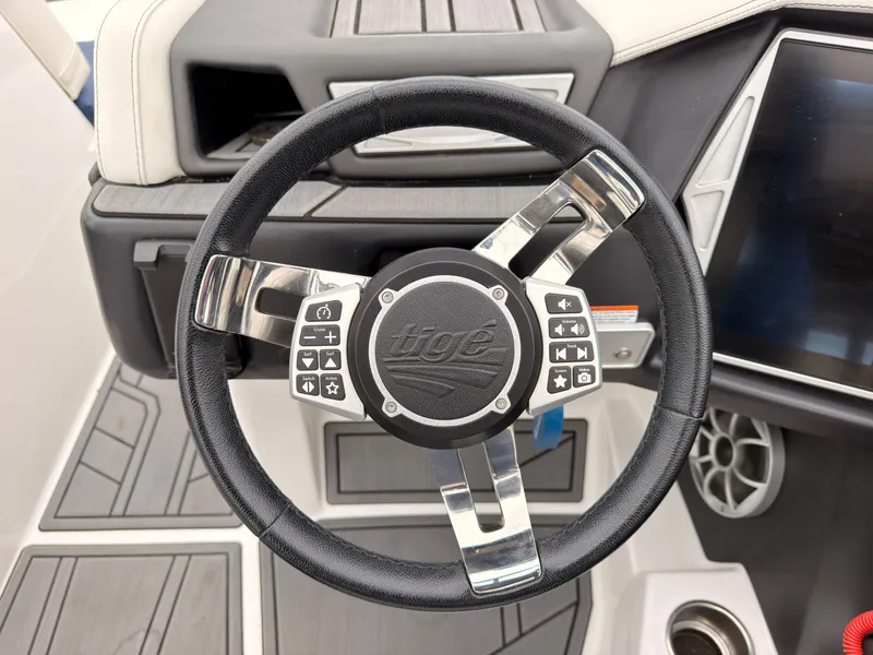 Slide: The Image of The image shows the steering wheel of a 2021 Tigé 22RZX boat with modern controls. - 40