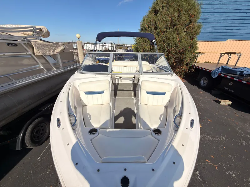 Slide: The Image of A 2008 Regal 1900 Bowrider with white interior and blue canopy, parked on an asphalt lot. - 35