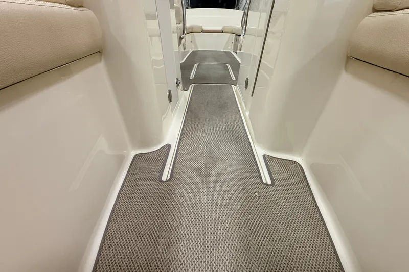 Slide: The Image of 2019 Chris-Craft Launch 27 interior walkway with beige seating and textured flooring. - 24