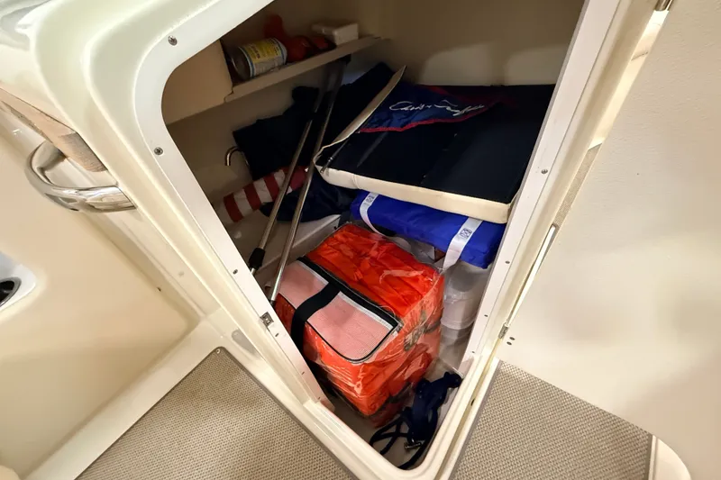 Slide: The Image of Storage compartment in a 2019 Chris-Craft Launch 27 boat, containing safety equipment and supplies. - 25