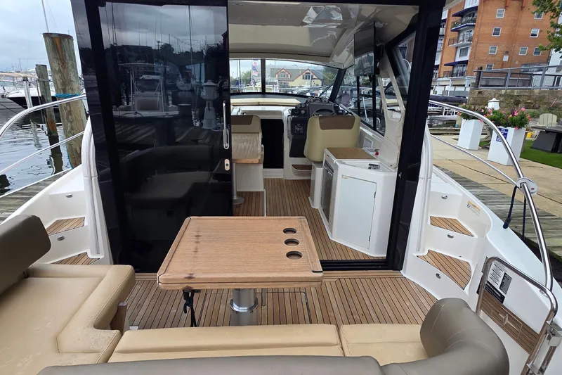 Slide: The Image of 2015 Bavaria 360 Sport HT yacht interior with seating, table, and helm at marina. - 10
