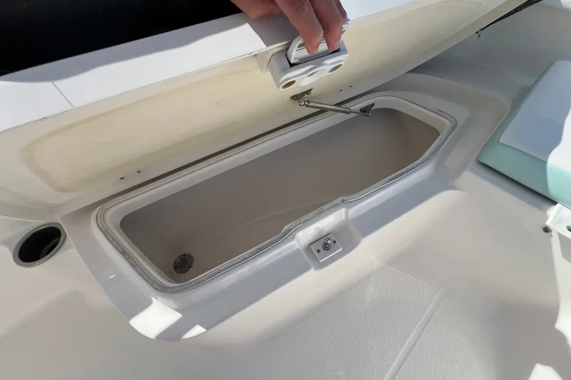 Slide: The Image of 2024 Robalo R200 Center Console boat storage compartment open with hand lifting lid. - 15