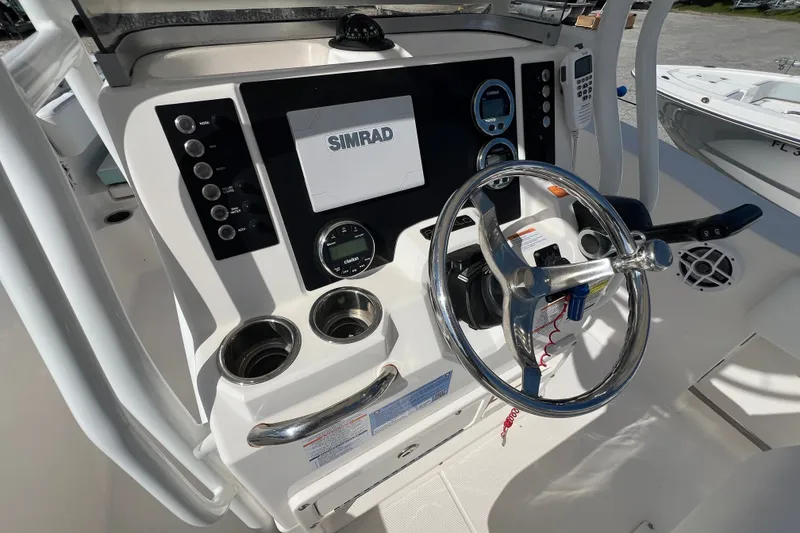 Slide: The Image of 2024 Robalo R200 Center Console boat dashboard with Simrad display and steering wheel. - 13