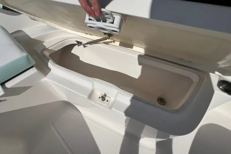 Slide: The Image of 2024 Robalo R200 Center Console storage compartment with open lid and hand visible. - 16