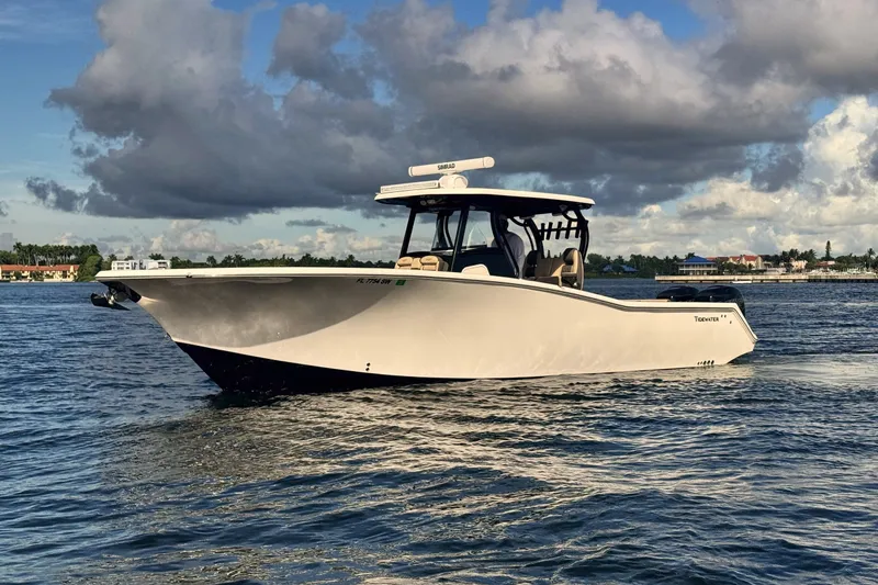 The Image of 2019 Tidewater 320 CC Adventure boat cruising on a calm sea under a cloudy sky. - 0