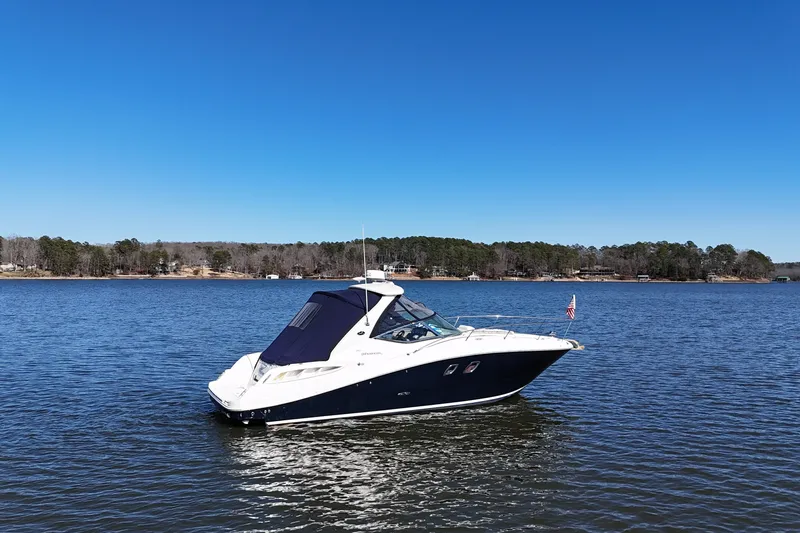 Slide: The Image of 2007 Sea Ray Sundancer 310 yacht on a serene lake under clear blue skies. - 2